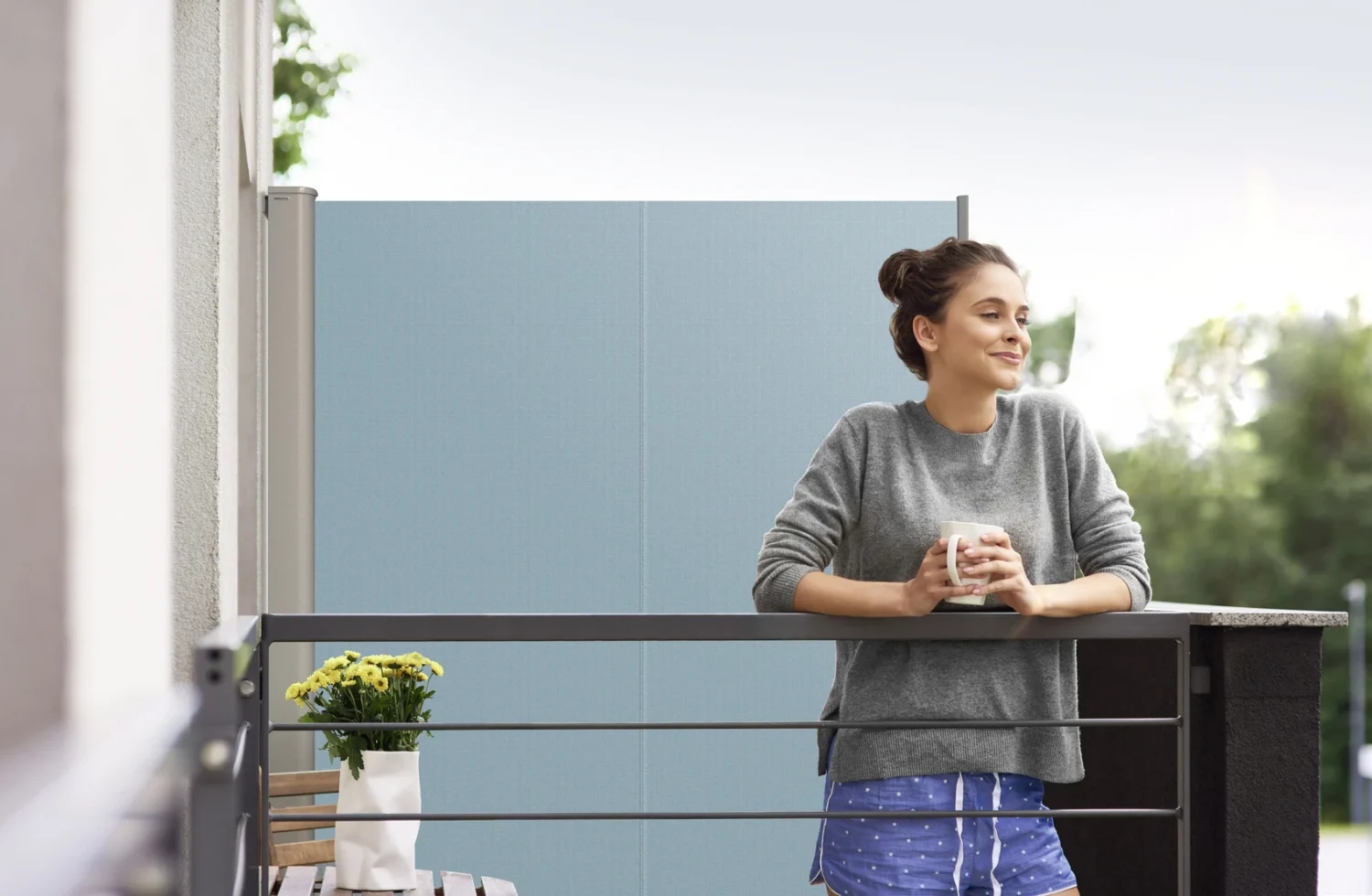 Frau genießt Kaffee auf Balkon vor Sichtschutz